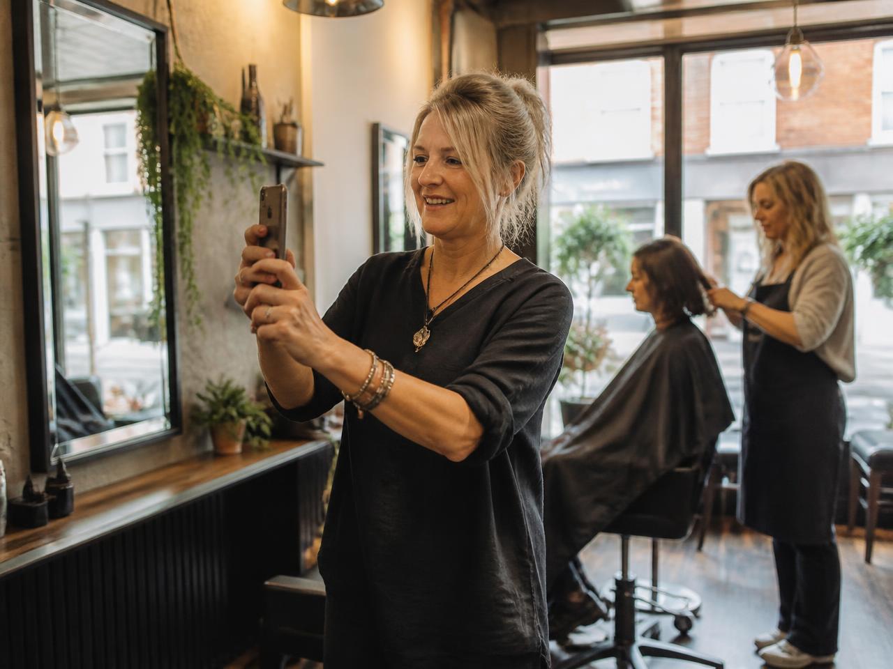 Salon owner creating social media content on her phone
